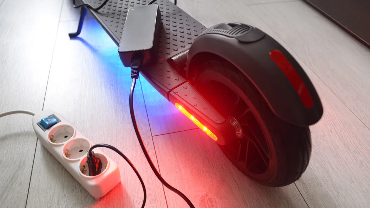 Elektrischer Roller beim Laden an einer Steckdose